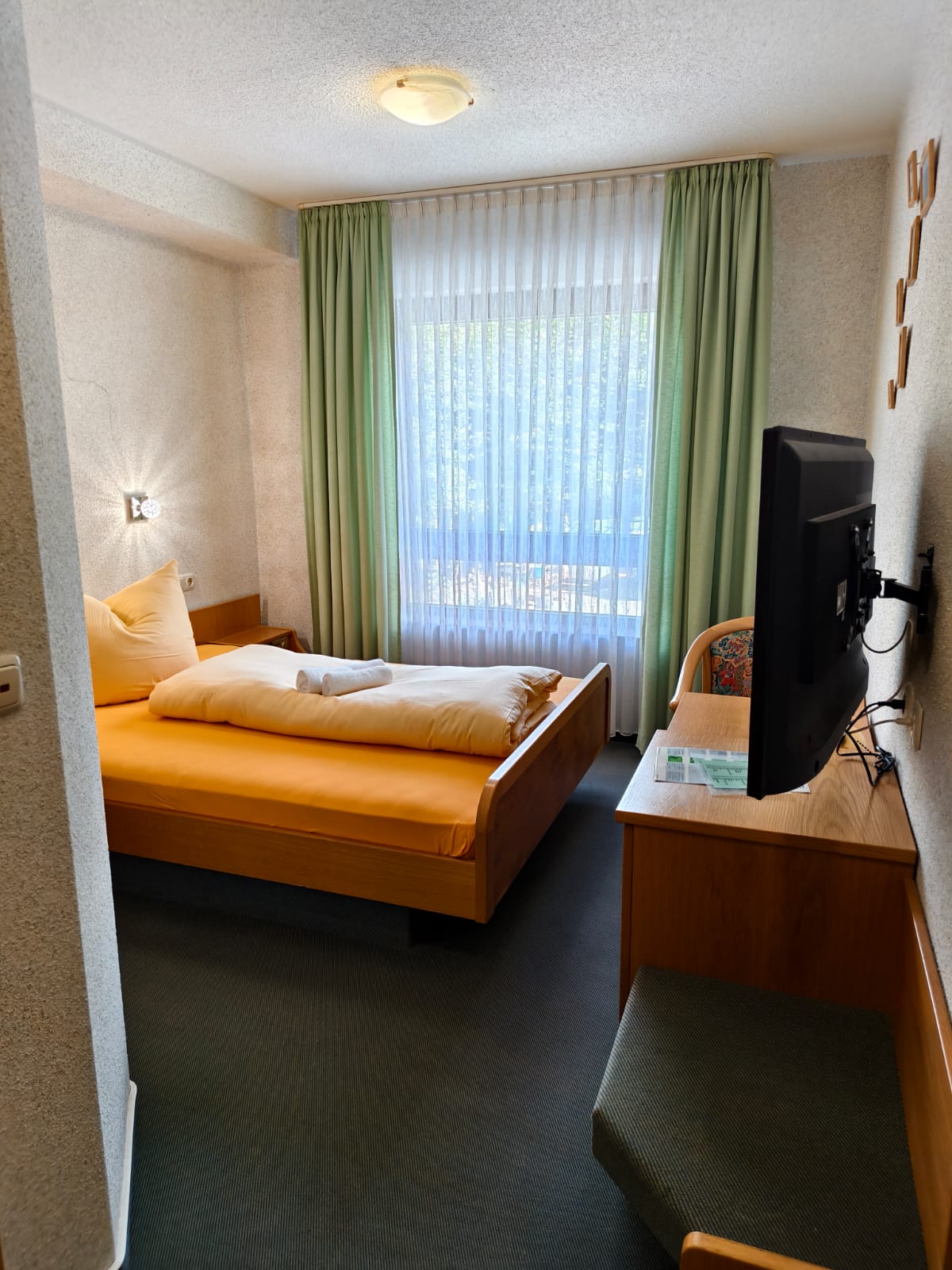 Einzelzimmer mit Bett und Fernseher